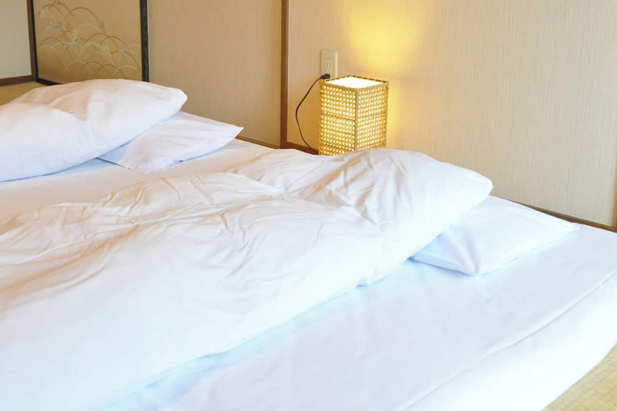 Une chambre d’hôtel avec un lit, des oreillers et une lampe fixée au mur.