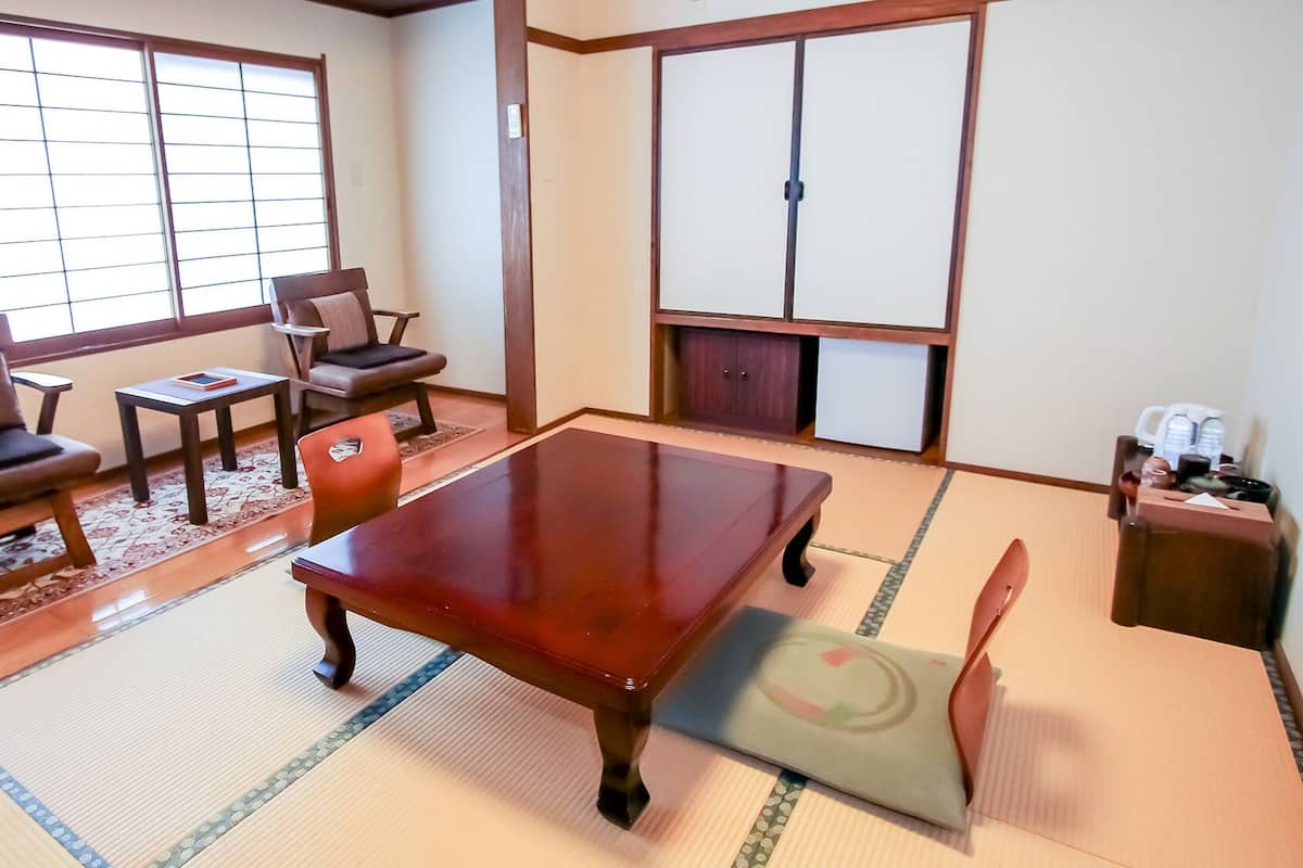 Une pièce de style japonais traditionnel, avec un sol recouvert de tatamis, une petite table en bois et une porte coulissante.