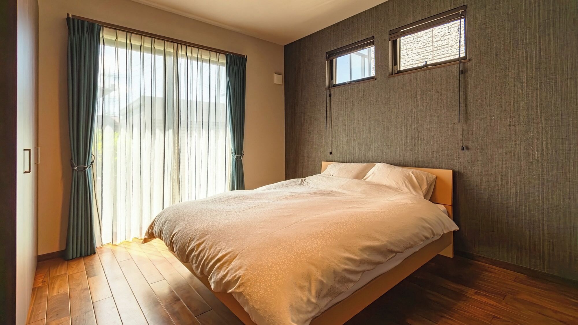 A bedroom with a bed, a window, and a curtain.