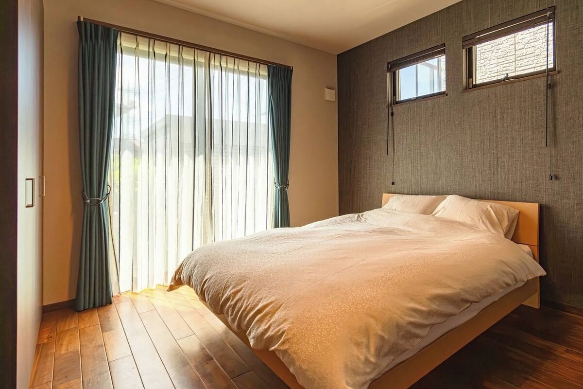 Une chambre à coucher avec un lit, une fenêtre et un rideau.
