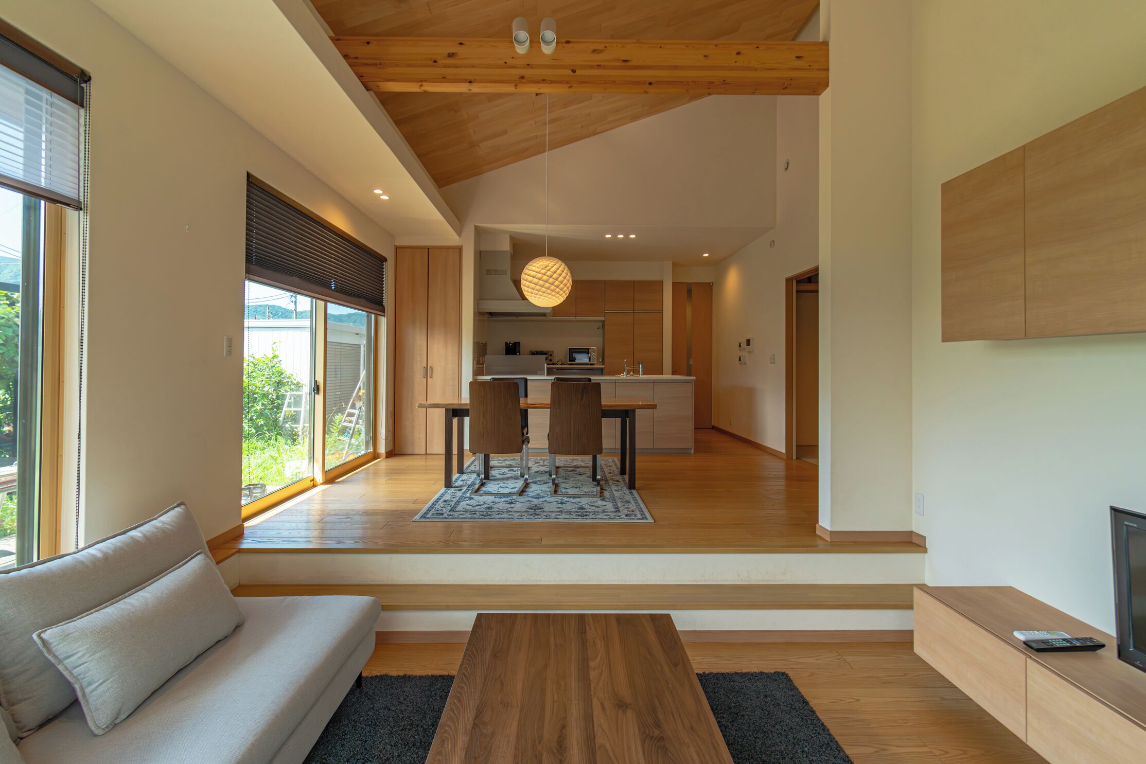 A modern interior with a sofa, wooden coffee table, and a kitchen in the background.