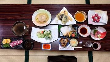 A wooden table with various Japanese dishes, including sushi, sashimi, and a bowl of soup.