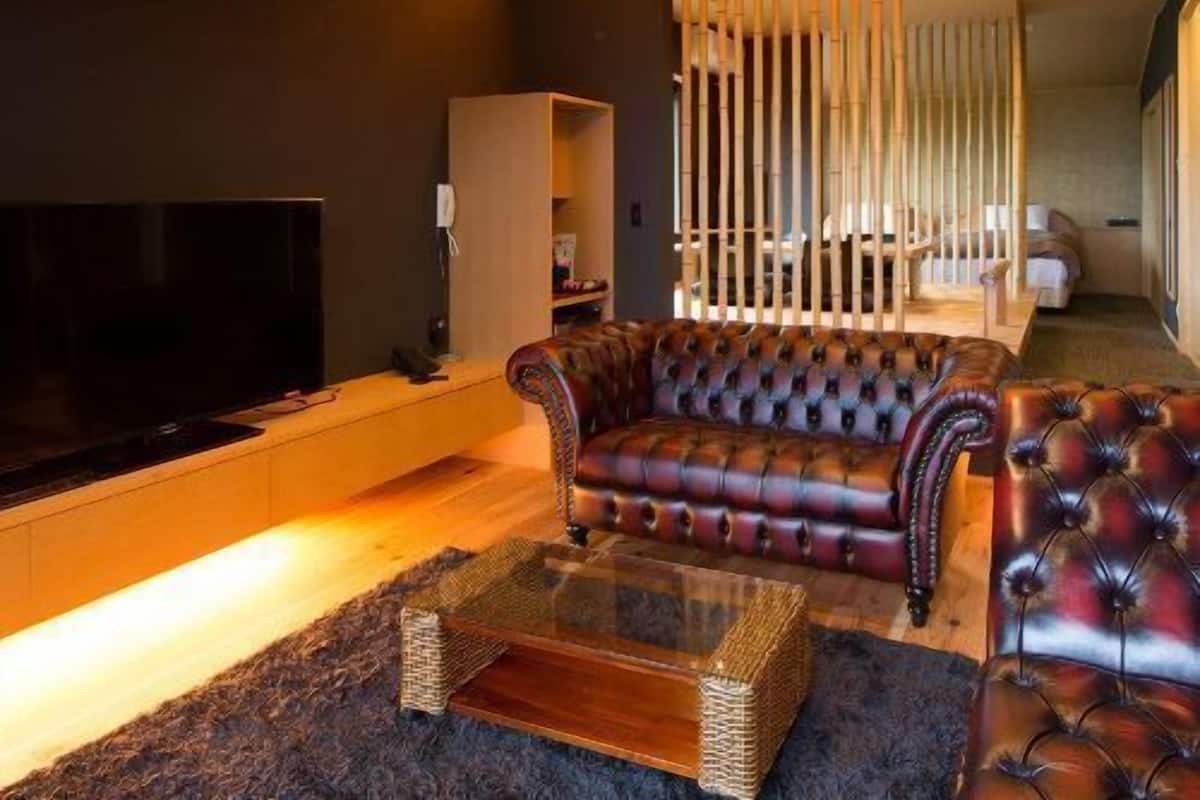 Un salon moderne doté d’un grand téléviseur à écran plat, de canapés en cuir, d’une table basse en verre et d’un plafond en bois.