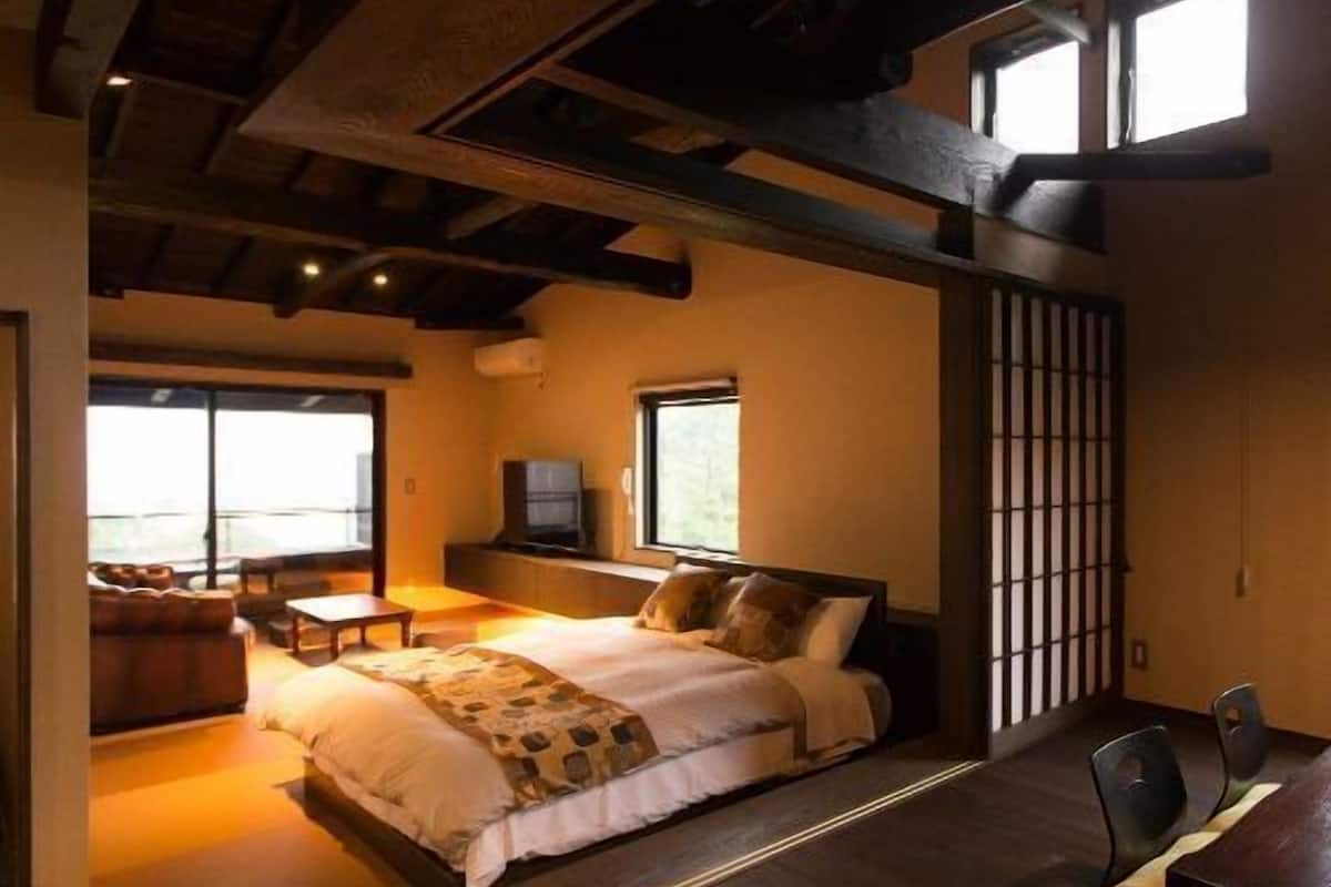 Une chambre à coucher avec un lit, une télévision, un canapé et une table à manger.