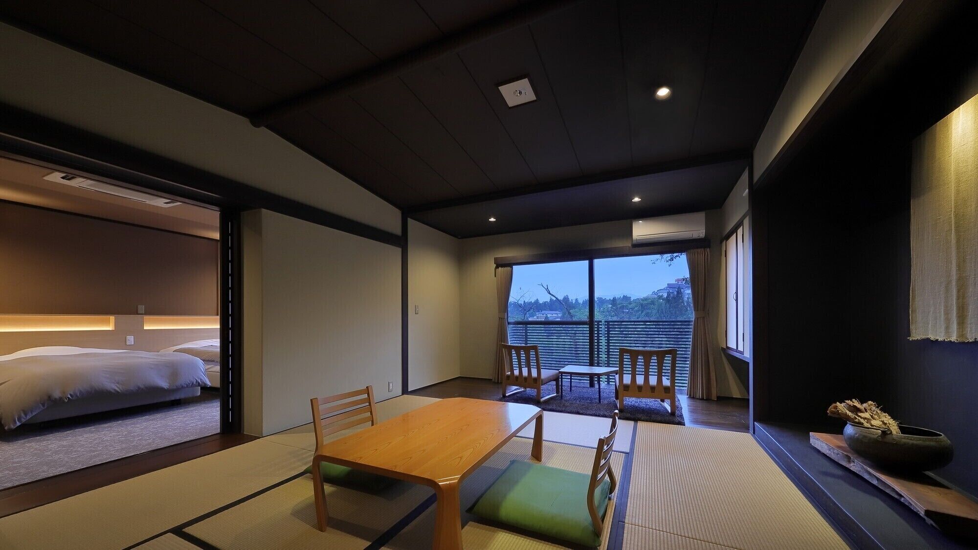 Habitació japonesa tradicional amb tatami, una taula baixa i vista a la ciutat.