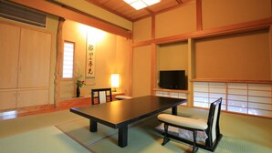 A traditional Japanese room with tatami flooring, a low table, chairs, a television, and a sliding door. - Kansuirou (Kaga)