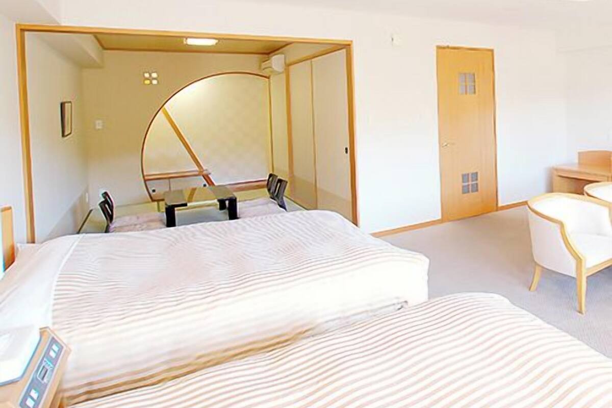 A hotel room with a bed, a desk, a chair, and a mirror.