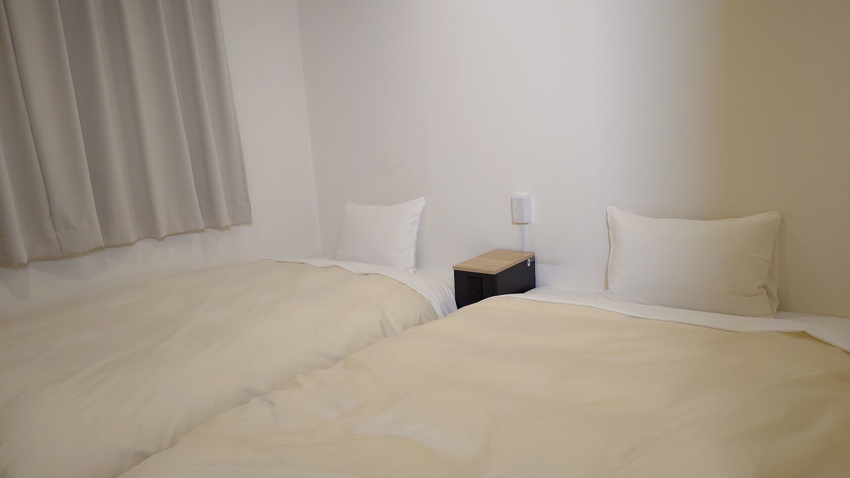 Ein Hotelzimmer mit zwei Betten, einem Nachttisch und einer Wandleuchte.