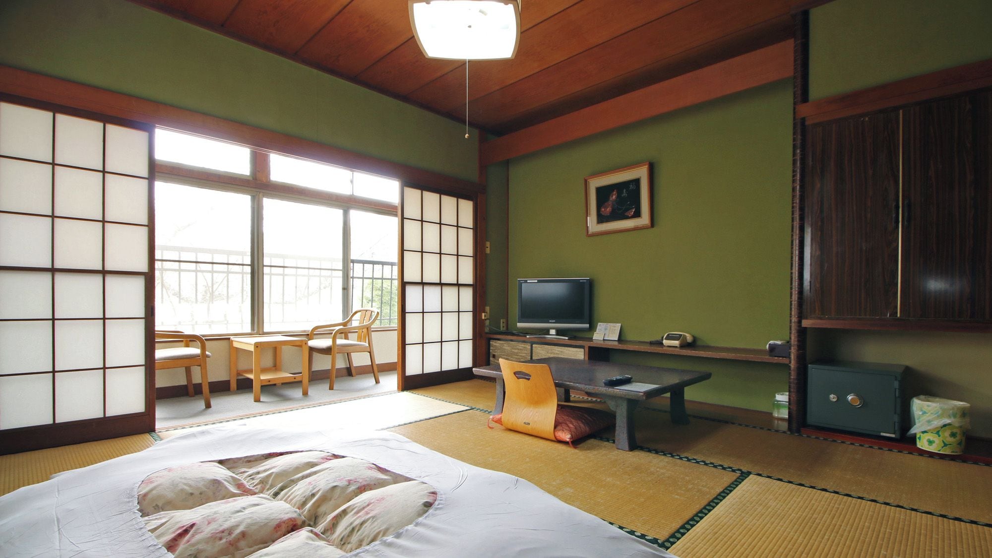 Una habitación japonesa tradicional con suelo de tatami, una cama, un televisor y un escritorio.