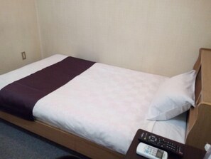 A single bed with a white and purple bedspread, a wooden headboard, and a remote control on a wooden nightstand. - Green Hotel Kobayashi (Kobayashi)