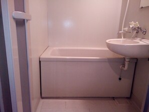 A bathroom with a white bathtub, a sink, and a toilet. - Green Hotel Kobayashi (Kobayashi)