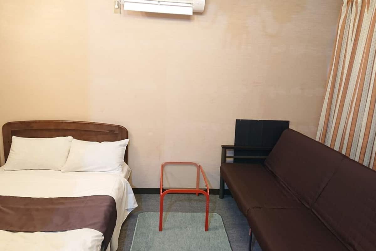 Habitación de hotel con cama, una silla, un sofá y una mesita.
