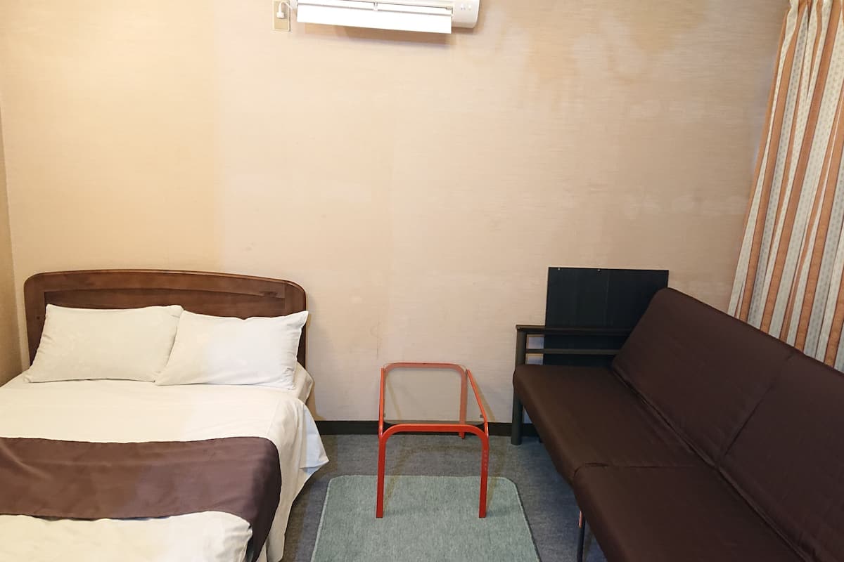 Una habitación de hotel con una cama, un sofá, una mesita y un televisor.