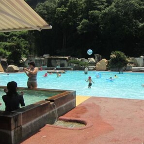 A swimming pool with a water slide, surrounded by rocks and trees. - Shuzenji Tokinosumika Hotel Olive Tree/ Hyakuwarai (Izunokuni)