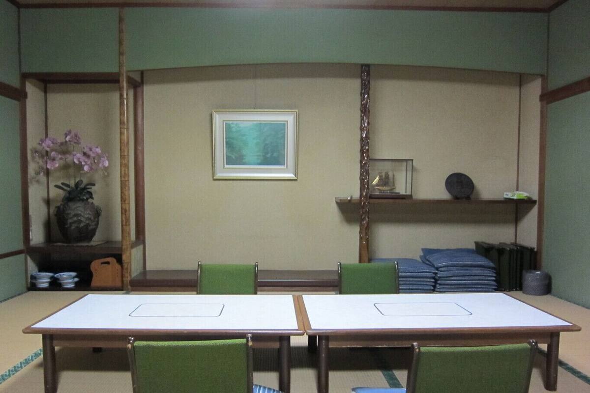 Una habitación japonesa tradicional con suelo de tatami, una mesa baja y sillas verdes.