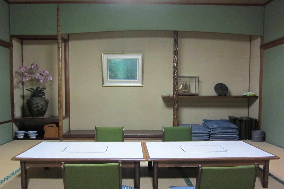 Une pièce de style japonais traditionnel, avec un sol recouvert de tatamis, une table basse et des chaises vertes.