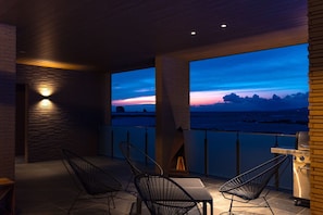 A balcony with a view of the sea at dusk, a grill, and modern chairs. - Ezra Villa Shirahama (Shirahama)