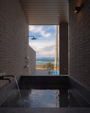 A modern bathroom with a built-in bathtub, a showerhead, and a view of the ocean. - Ezra Villa Shirahama (Shirahama)