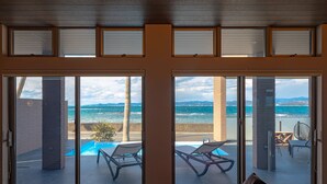 Une pièce dotée de grandes portes-fenêtres coulissantes donnant sur un balcon avec une piscine et des chaises longues.