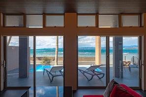 Une pièce dotée de grandes portes-fenêtres coulissantes donnant sur un balcon avec une piscine et des chaises longues.