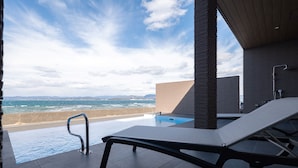 Un espace aménagé au bord de la piscine, offrant une vue sur l’océan, avec un fauteuil de relaxation et une architecture moderne.