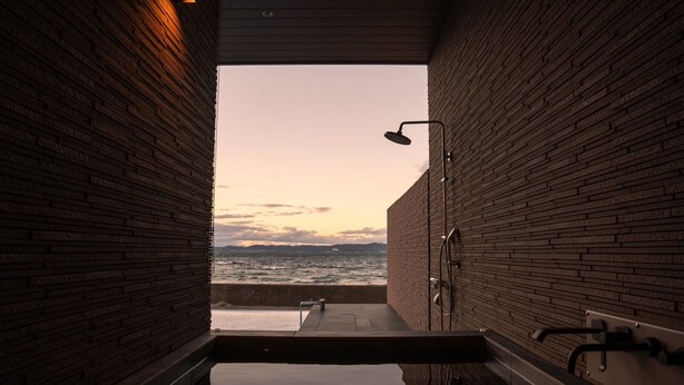 Un espace spa avec vue sur la mer, une douche et un banc.