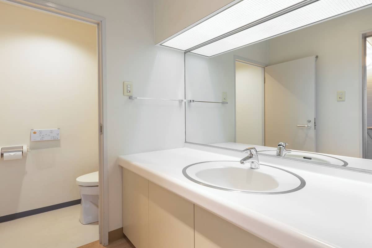Een moderne badkamer met een wit wastafel, spiegel en douche.