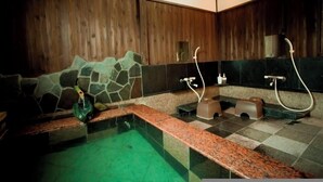 A spa area with a stone wall, a small pool, and two showerheads.