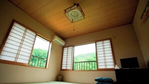 A room with tatami flooring, sliding shoji doors, a ceiling fan, and a TV.