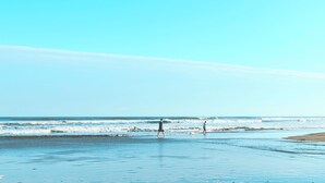 A beach with two people walking, clear skies, and calm ocean waves. - Eight Village (Kujukuri)
