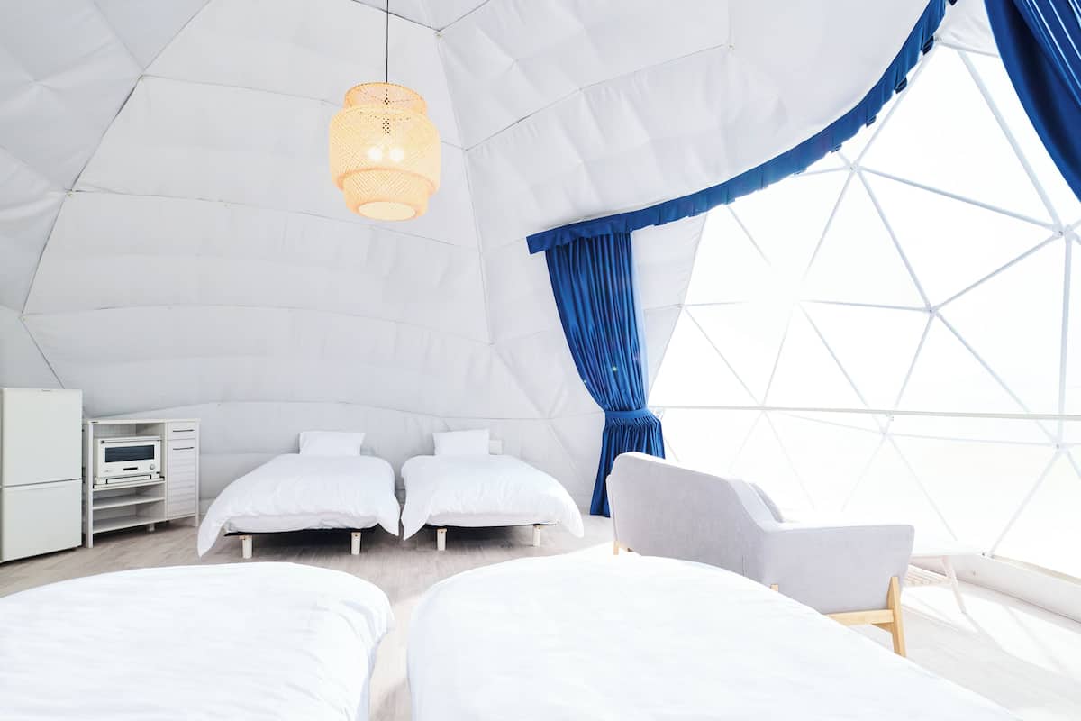 An igloo-shaped room with two beds, a desk, and a chair.