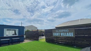 A gated entrance to Glamping Eight Village with a clear sky and a grassy lawn. - Eight Village (Kujukuri)