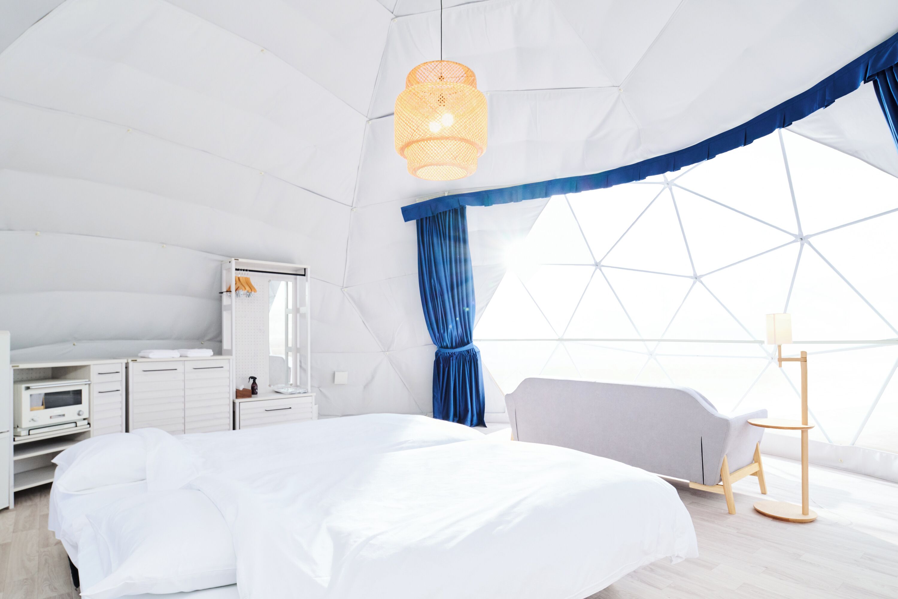 A modern, well-lit bedroom with a bed, bedside table, and a large window.