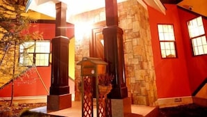 Una casa moderna con fachada de piedra, exterior rojo y un acceso destacado con un alero blanco.