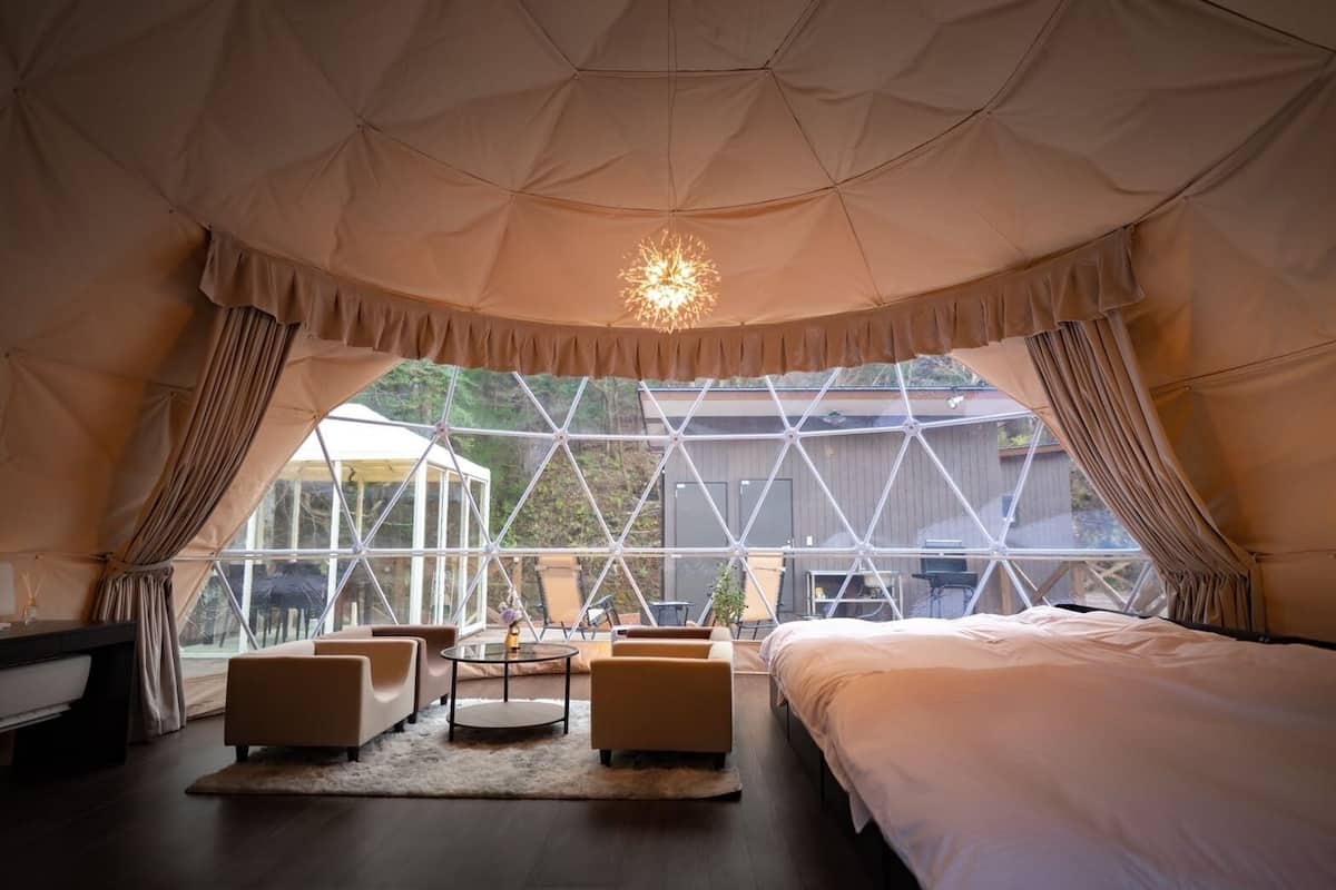 Ein Zelttyp-Zimmer mit einem Bett, zwei Sofas, einem kleinen Tisch und einer Chandelier.