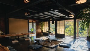 Una habitación tradicional japonesa con suelo de tatami, una mesa baja, cojines y un pequeño hogar.