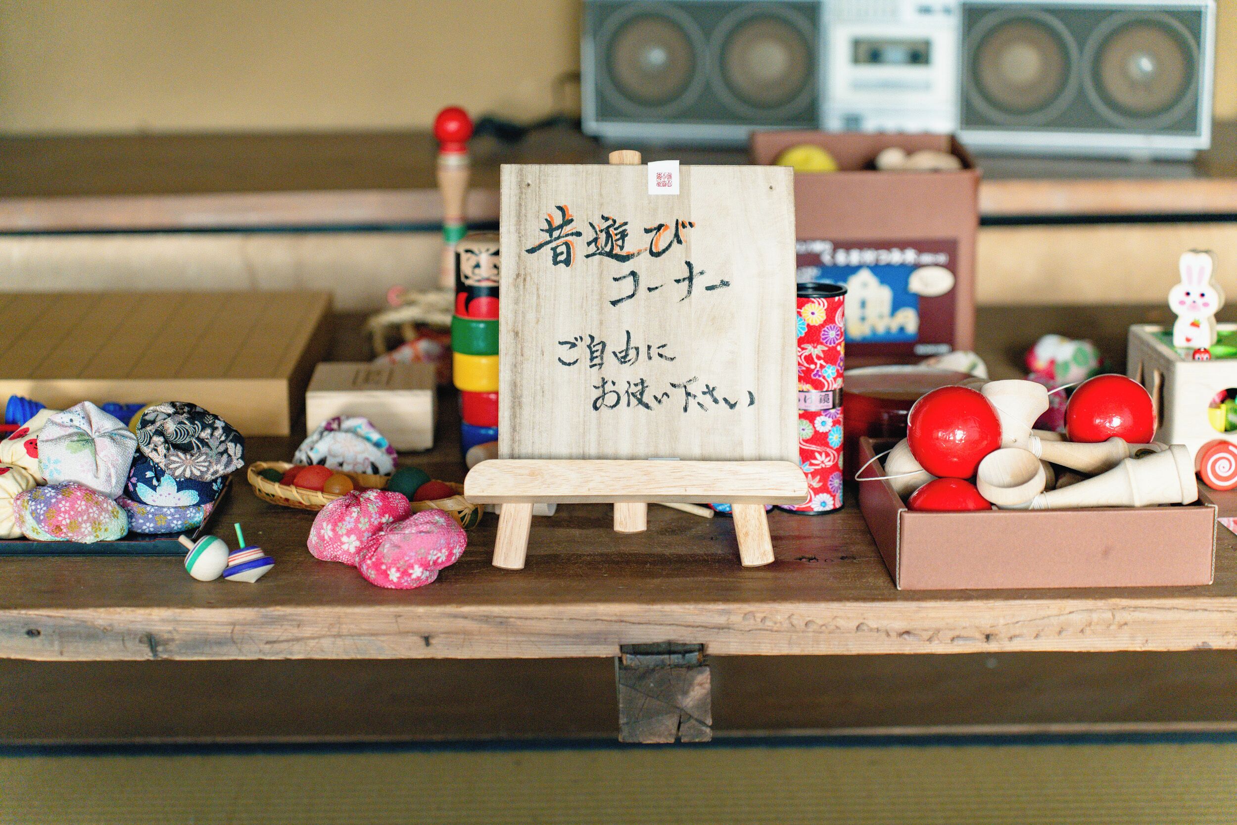 A wooden table with various items including a small wooden sign, colorful balls, and a box of red and white items.