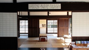 Una habitación japonesa tradicional con suelo de tatami, puertas correderas y una mesa baja.