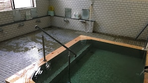Ein Schwimmbecken mit Holzterrasse, gefliesten Wänden und Desinfektionsmittelspendern.