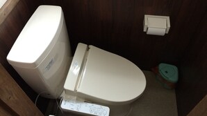 Ein kleines, kompaktes Badezimmer mit Toilette, Handtrockner und Mülleimer.