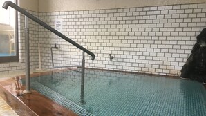 Ein Schwimmbecken mit einer mit Fliesen verkleideten Wand, einem Holzboden und einem Metallgeländer.