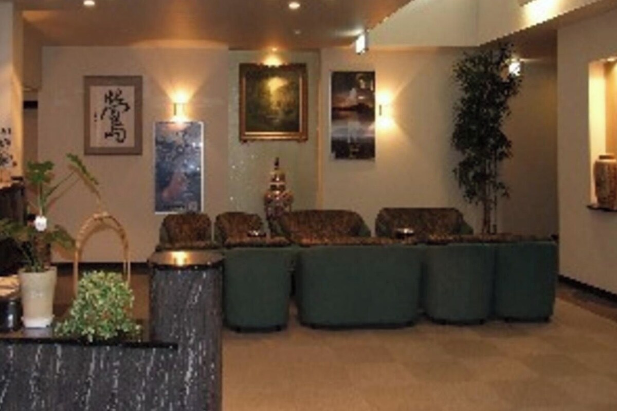 A hotel lobby with a reception desk, seating area, and artwork on the walls.