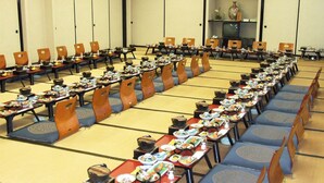 A conference room with rows of tables set for a meal, chairs, and a television on a shelf. - Oshuku Onsen Hotel Uguisu (Shizukuishi)