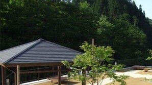 A covered outdoor area with a seating area, a small building, and a tree. - Oshuku Onsen Hotel Uguisu (Shizukuishi)
