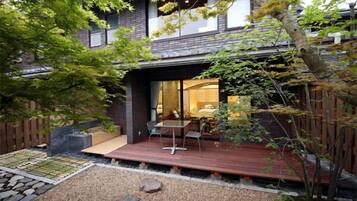 A modern house with a deck, a small garden area with rocks, and a wooden fence.