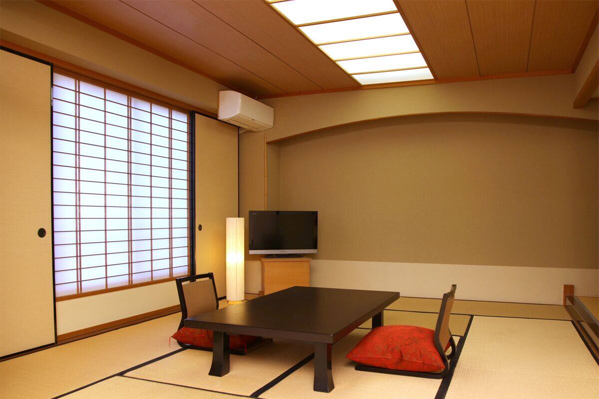 Een traditionele Japanse kamer met tatami vloerbedekking, een lage tafel en een televisie.