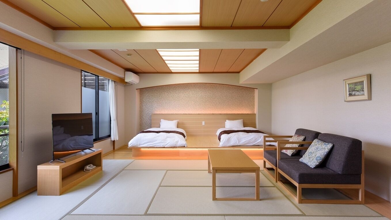 Quarto de hotel moderno com cama, sofá, televisão e uma pequena mesa.