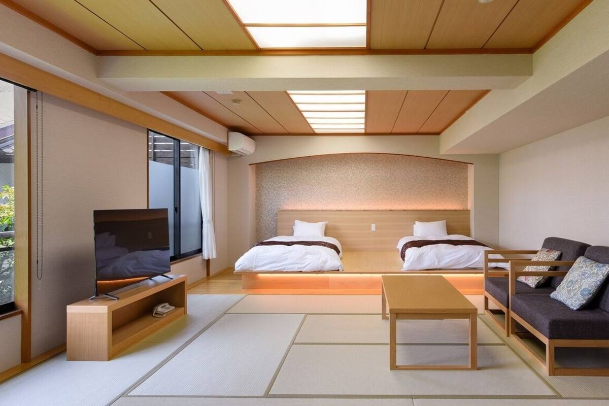 Een moderne hotelkamer met een bed, een bank, een televisie en een klein tafeltje.