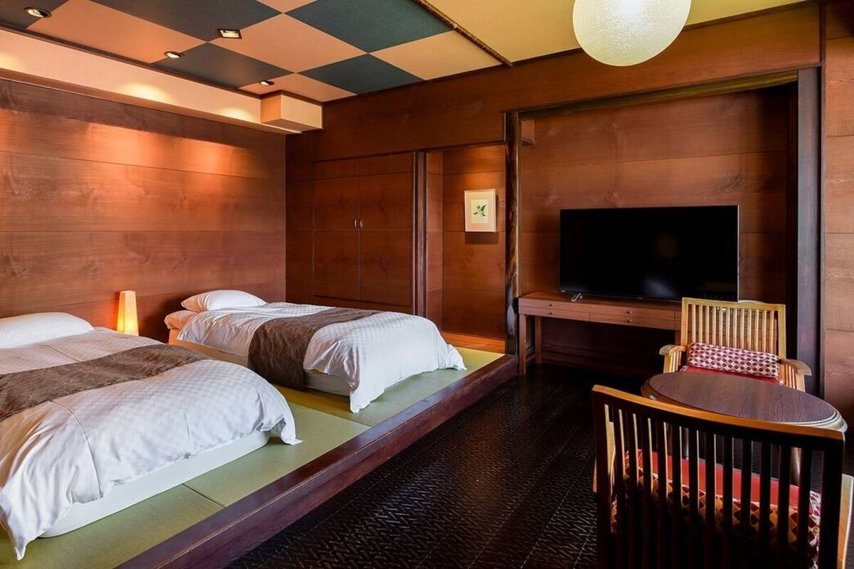 Een hotelkamer met twee bedden, een televisie, een houten stoel en een kleine tafel.