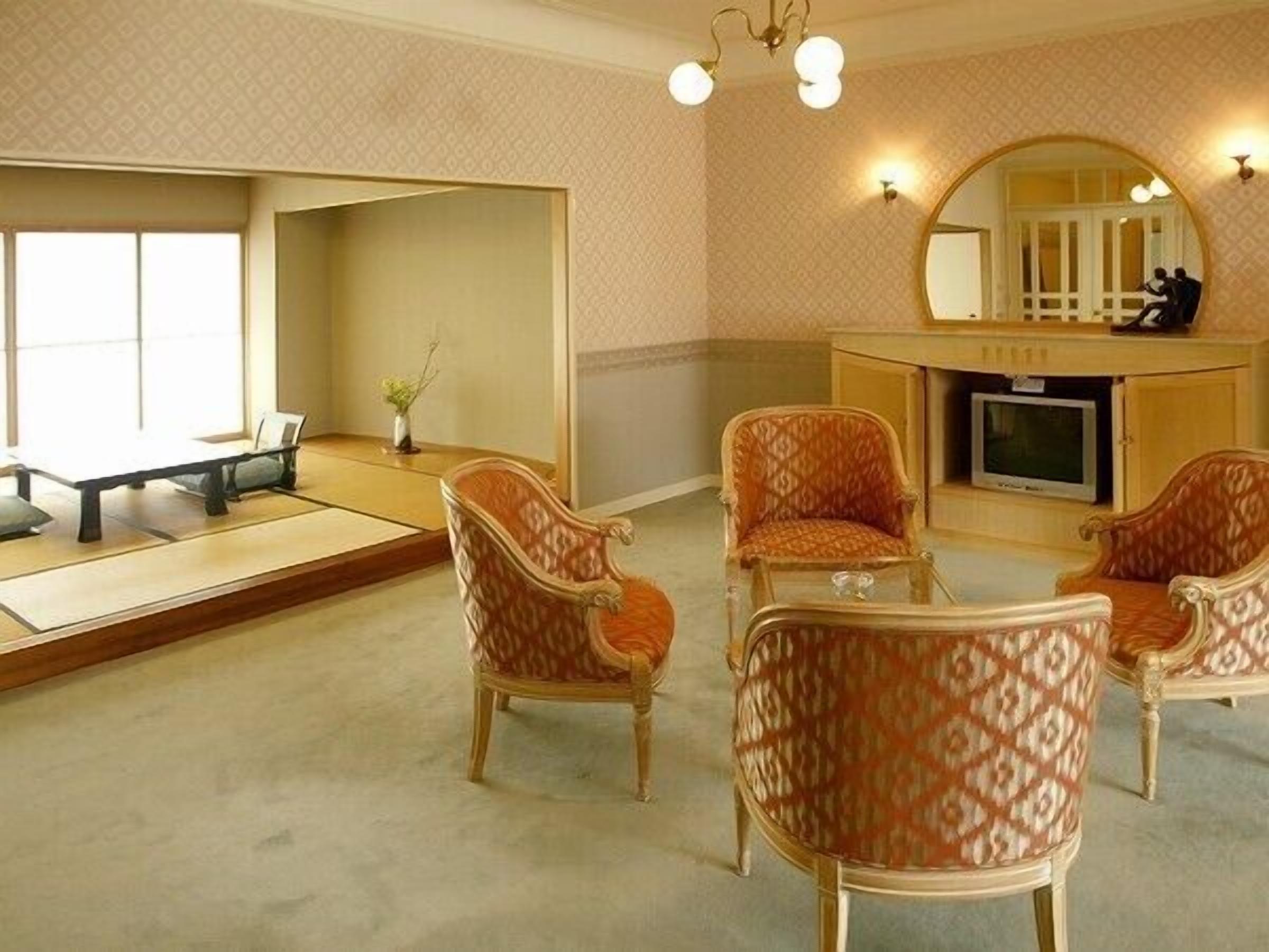 Um quarto em estilo japonês tradicional, com tatames, uma mesa baixa e quatro cadeiras estampadas.
